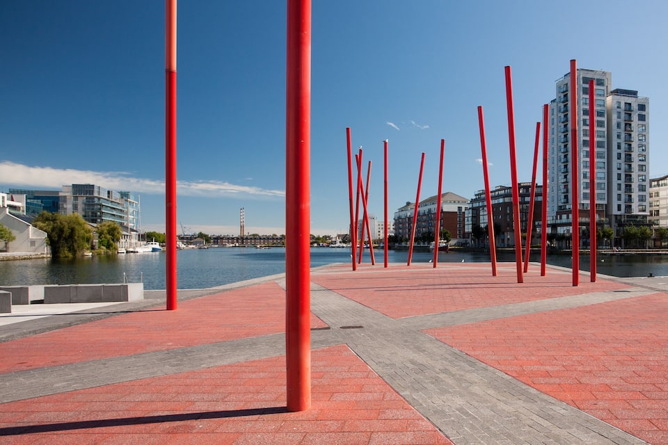 A waterfront promenade with red poles and a river.