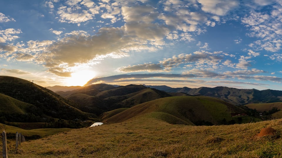 Rolling hills, a valley, and a distant sunrise.