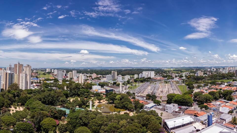 A cityscape with high-rise buildings, green parks, and a clear blue sky.