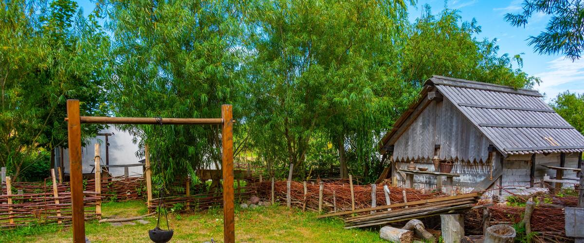A rustic farm with wooden structures, a metal roof, and a wooden fence.