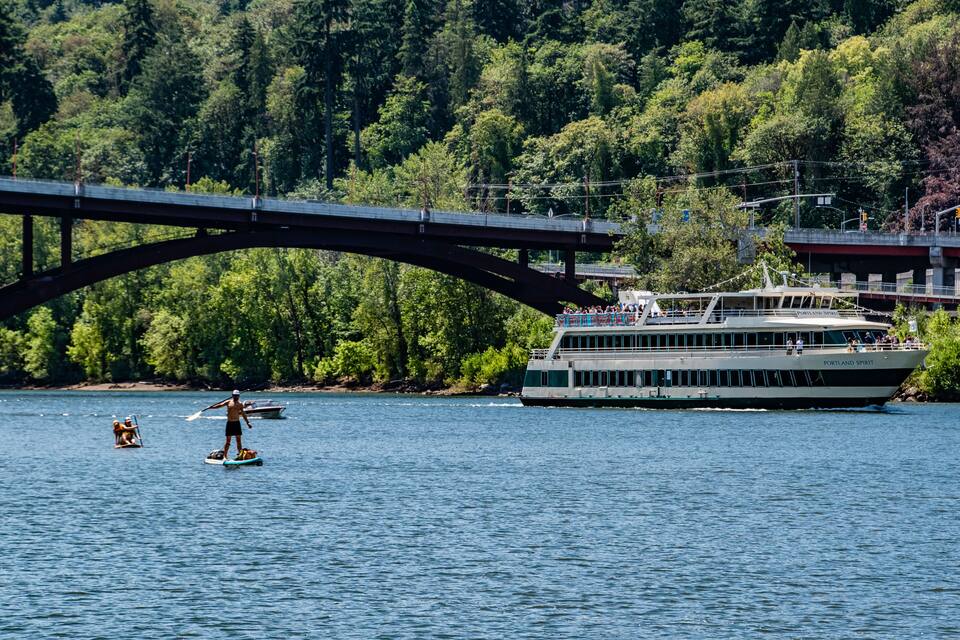 A river with a bridge, a paddleboarder, and a ferry named Portland Spirit.