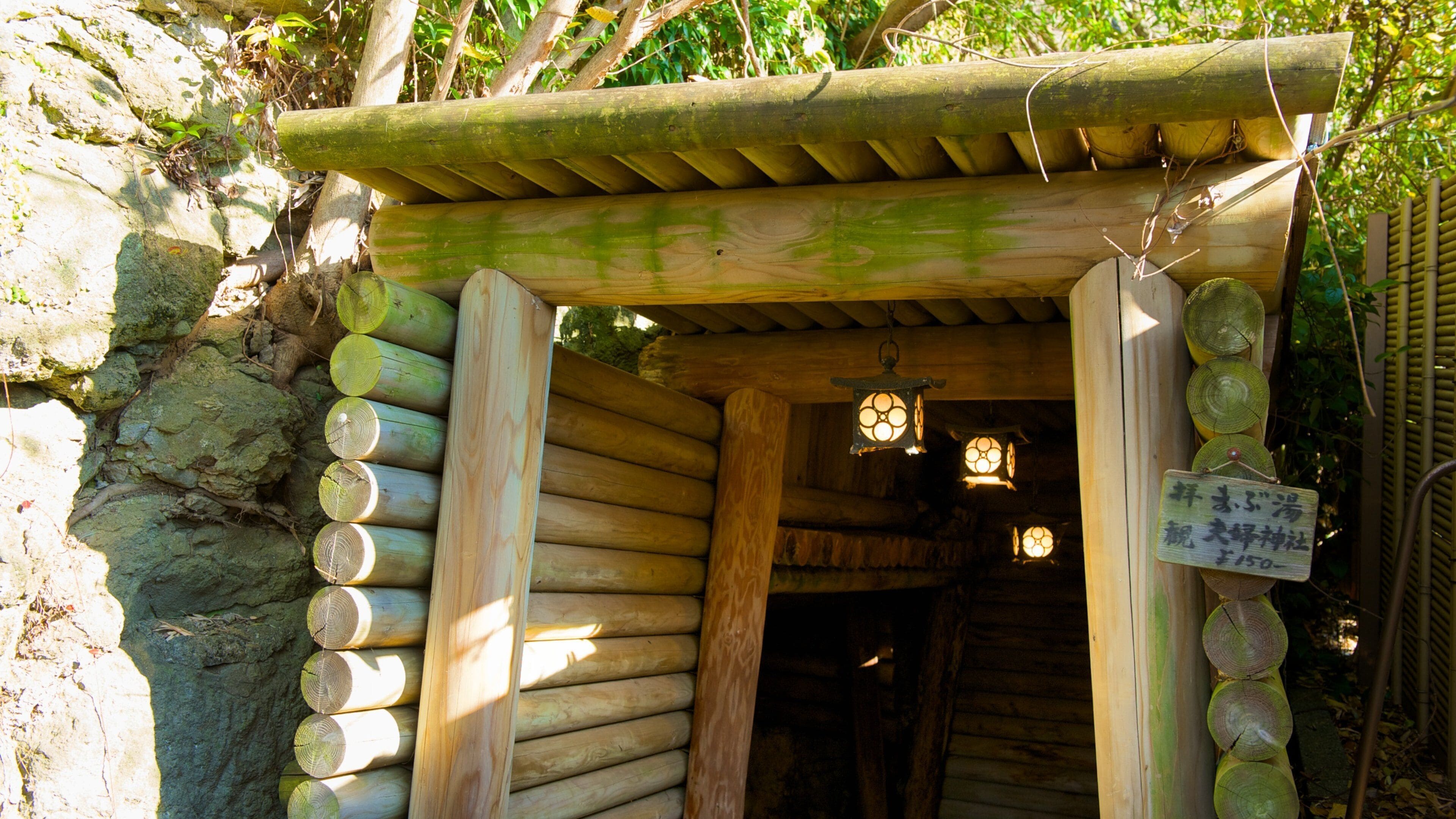 A traditional Japanese torii gate with a bamboo roof, surrounded by greenery.