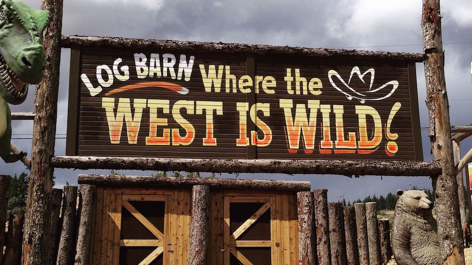 A sign for 'Log Barn' with a bear and a crocodile illustration.