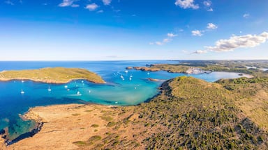 A coastal landscape with clear blue waters, rocky shores, and scattered boats.