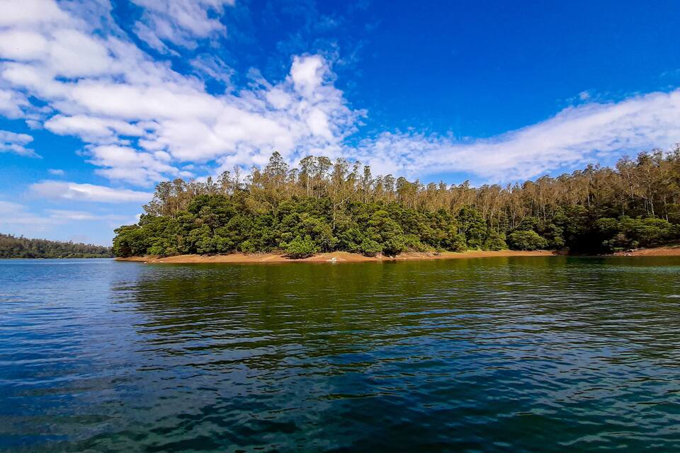 A calm lake with a forested island and a clear blue sky.