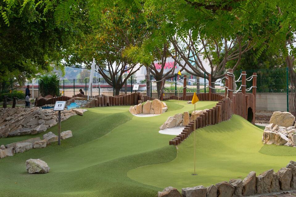 A miniature golf course with a green fairway, sand traps, and a wooden fence.