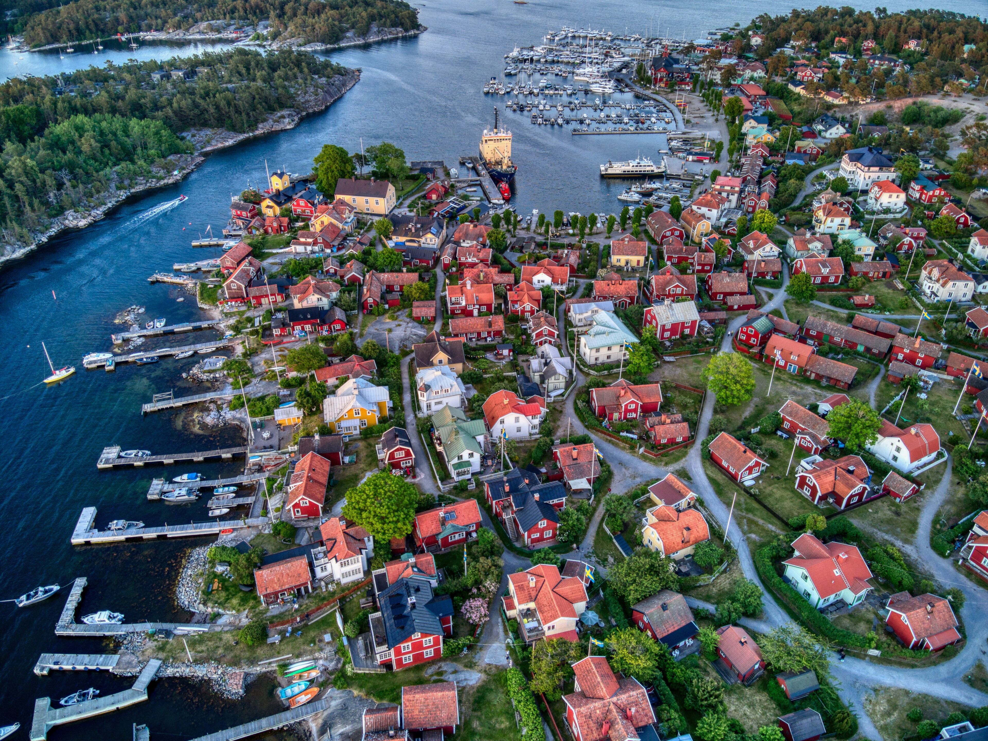A coastal village with red-roofed houses, a marina, and a prominent yellow building.