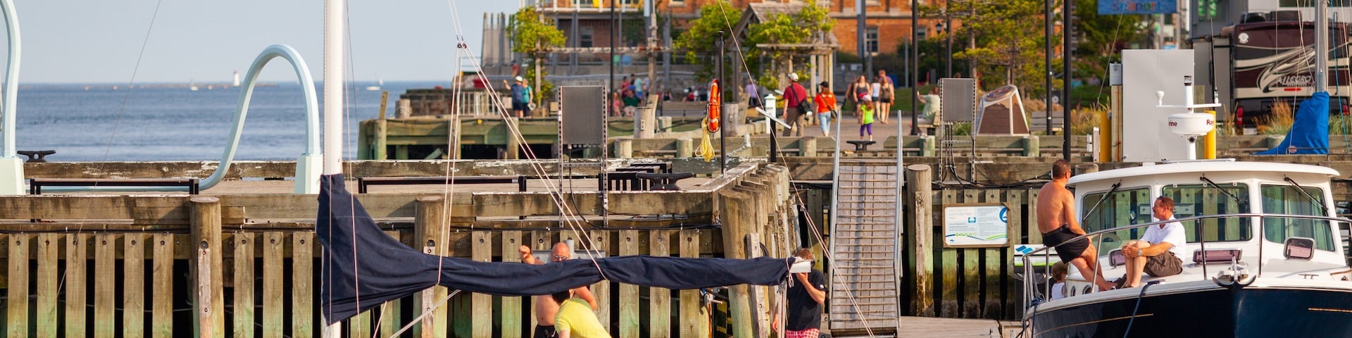 Un velero amarrado con gente a bordo, un muelle y un edificio al fondo.
