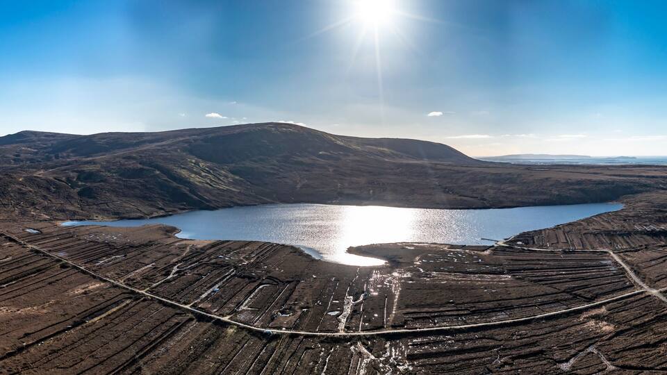 An aerial view of a volcanic landscape with a lake and terraced fields.