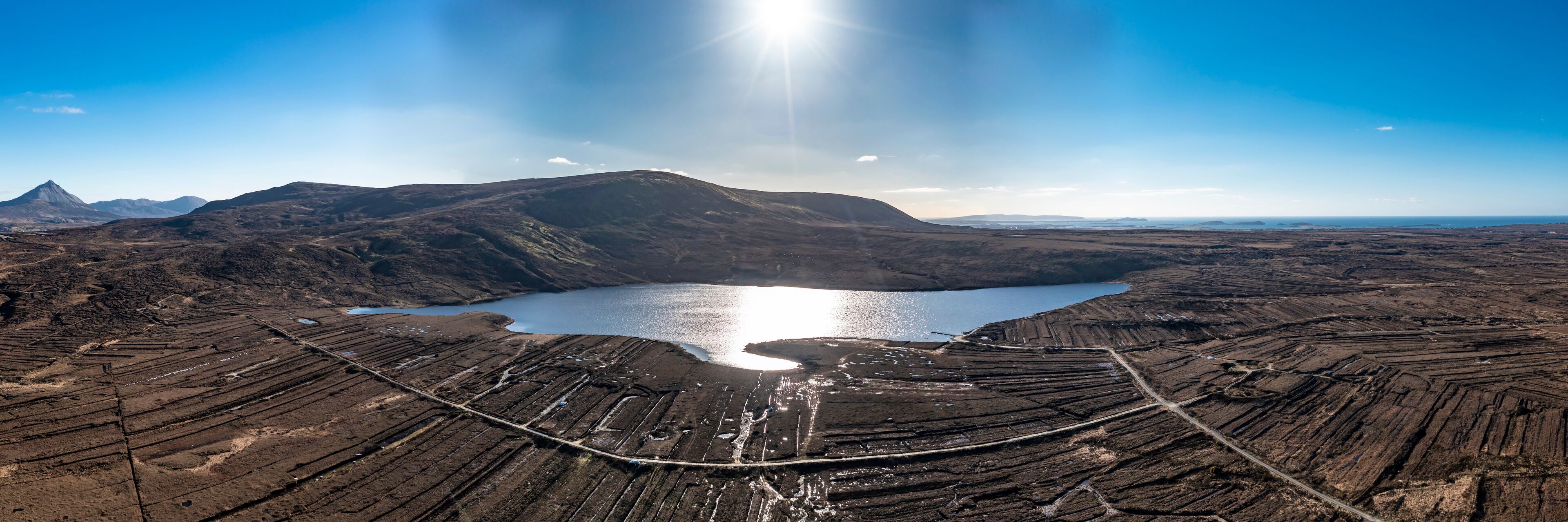 An aerial view of a volcanic landscape with a lake and terraced fields.