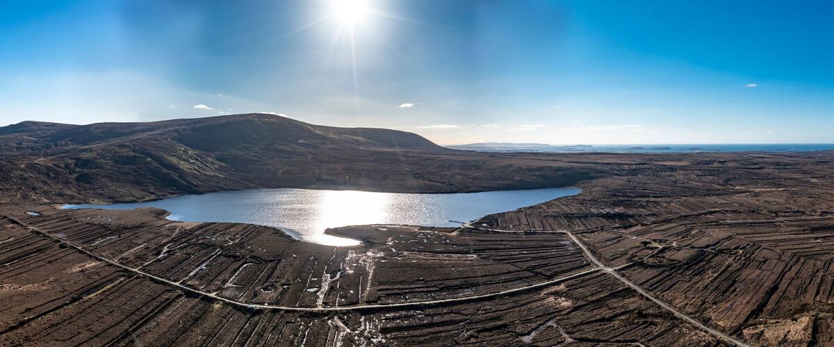 An aerial view of a volcanic landscape with a lake and terraced fields.