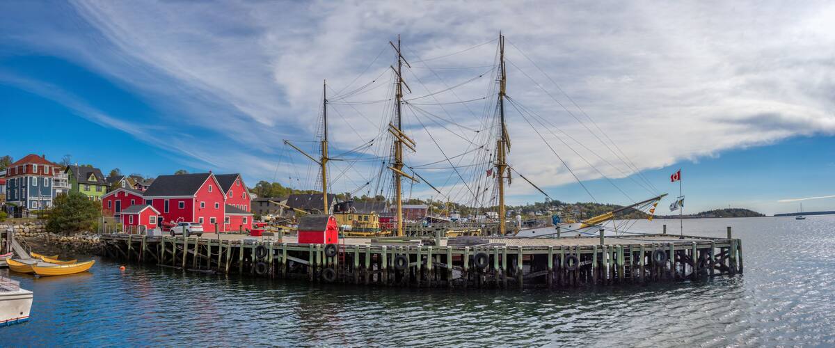 A historic ship docked at a pier with colorful buildings in the background.