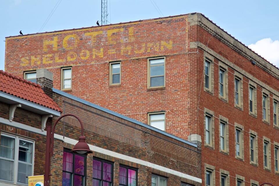 A red brick building with a large yellow sign that reads "HOTEL SHELDENHAM."