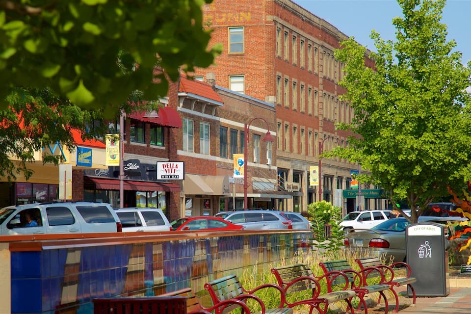 A street lined with parked cars, a mural, and various storefronts.