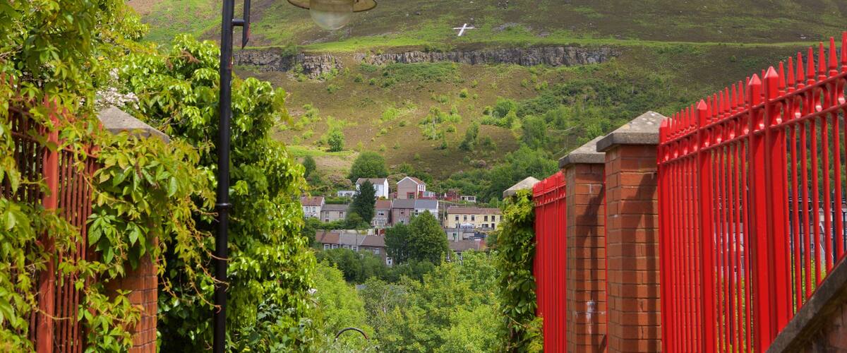 A hillside with houses, a red fence, and a street lamp.