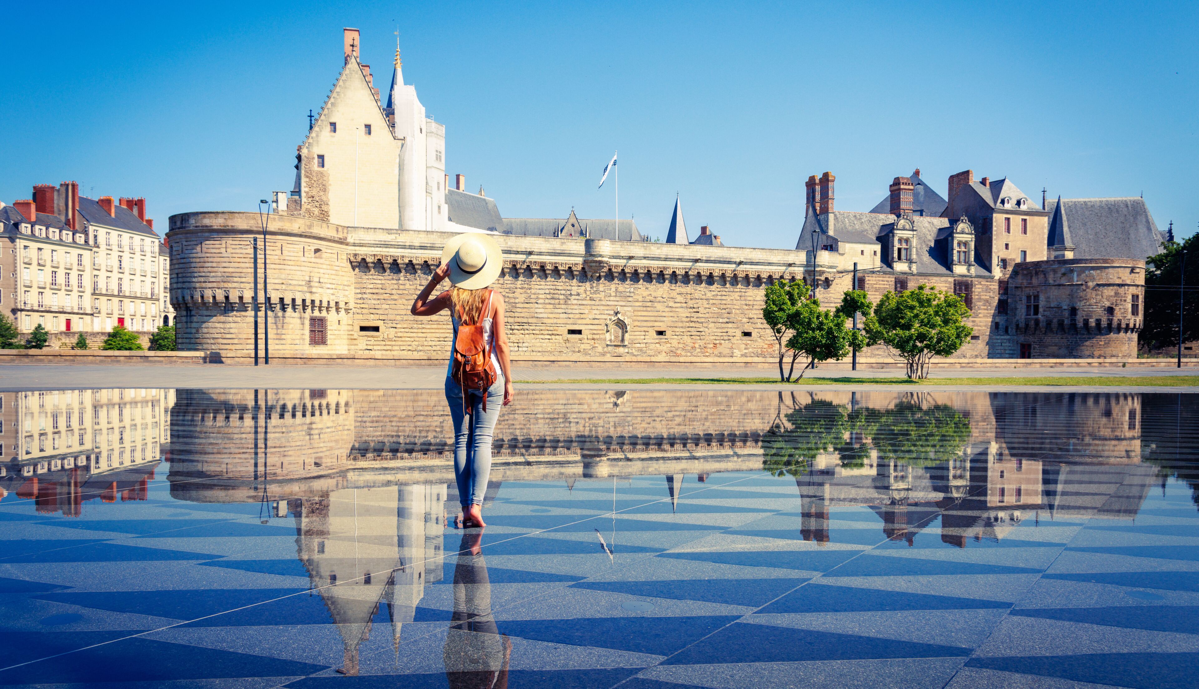 Woman walking in mirror water in Nantes- Loire-Atlantique,  Pays de la Loire in France- Castle of the Dukes of Brittany