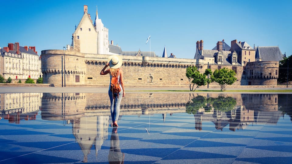 Woman walking in mirror water in Nantes- Loire-Atlantique, Pays de la Loire in France- Castle of the Dukes of Brittany