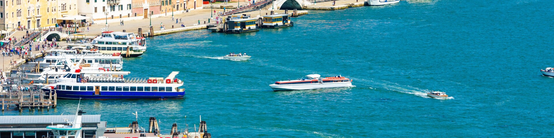 Port in Venice, Italy. Seafront with piers for tourist ships in Venetian lagoon. Cityscape of Venice in summer. City embankment taken from above. Concept of sea travel and vacation in Venice.