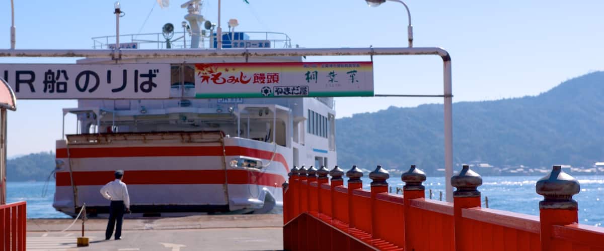 Fährhafen Miyajima welches beinhaltet allgemeine Küstenansicht und Bootfahren sowie einzelner Mann