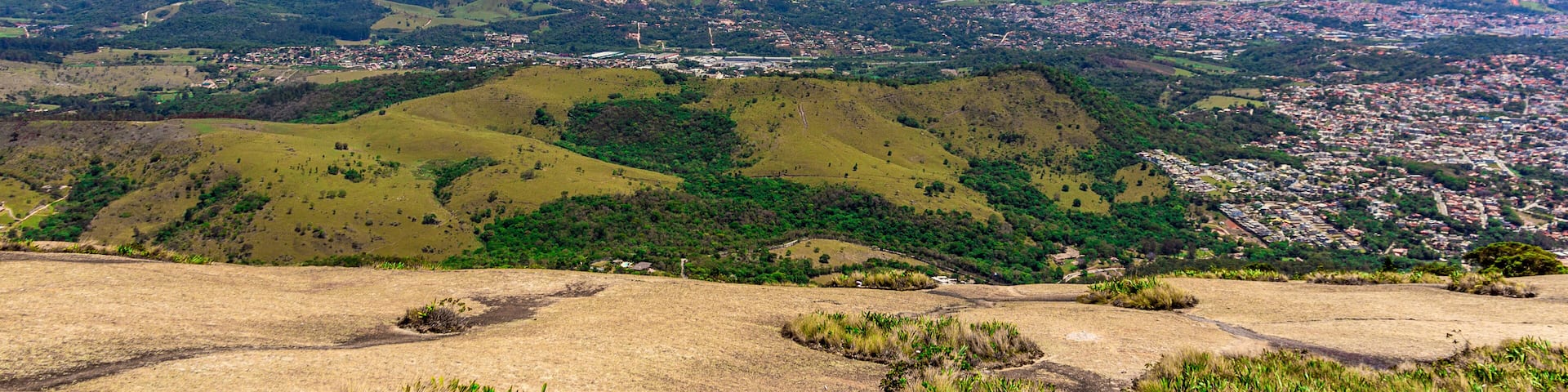 A panoramic view of a city nestled in rolling hills, with a clear sky above.