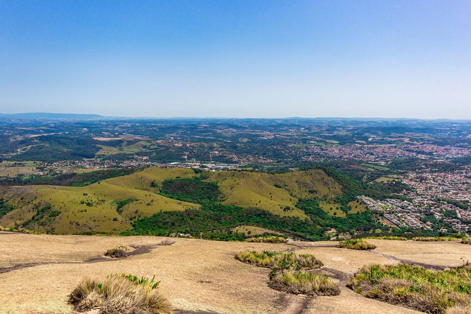 A panoramic view of a city nestled in rolling hills, with a clear sky above.