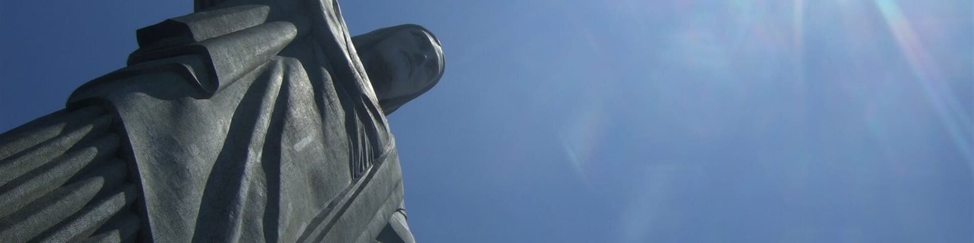 Una estatua con los brazos extendidos al cielo azul despejado.
