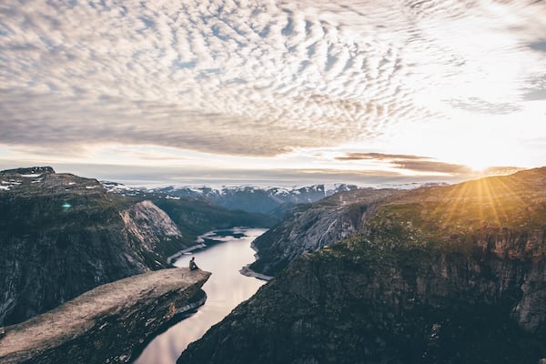 A mountainous landscape with a river flowing through a valley, surrounded by rugged cliffs.