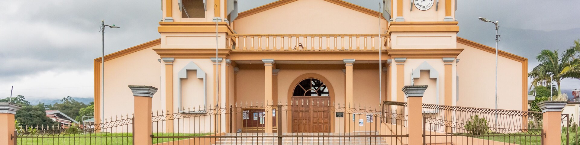 Una iglesia con dos cúpulas, un reloj y una entrada con reja.