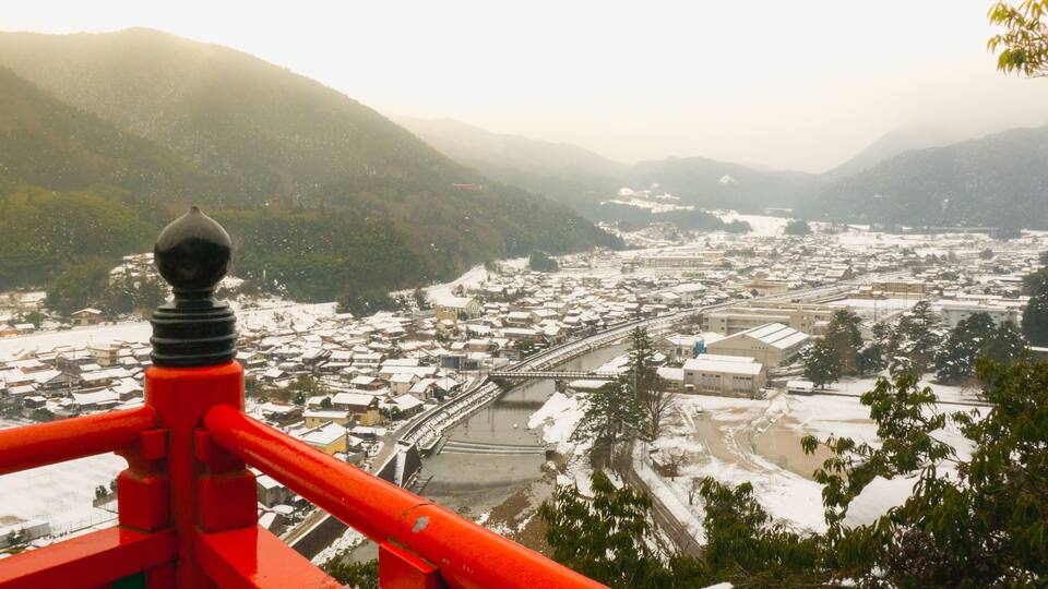 A snow-covered town with a river, surrounded by mountains.