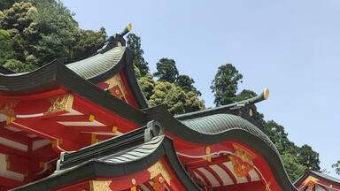 A traditional red and gold temple with ornate architecture and a staircase leading up to the entrance.
