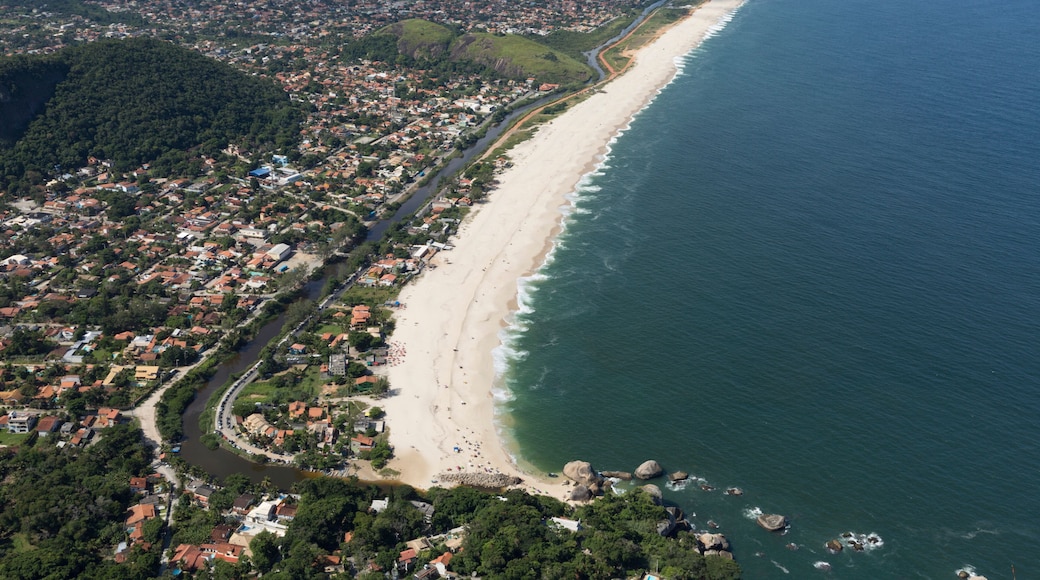 Ein Luftbild einer Küstenstadt mit langem Strand, dicht bebautem Stadtgebiet und umgebenden Hügeln.