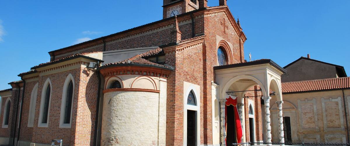 A historic church with a bell tower, arched windows, and a red statue in front.