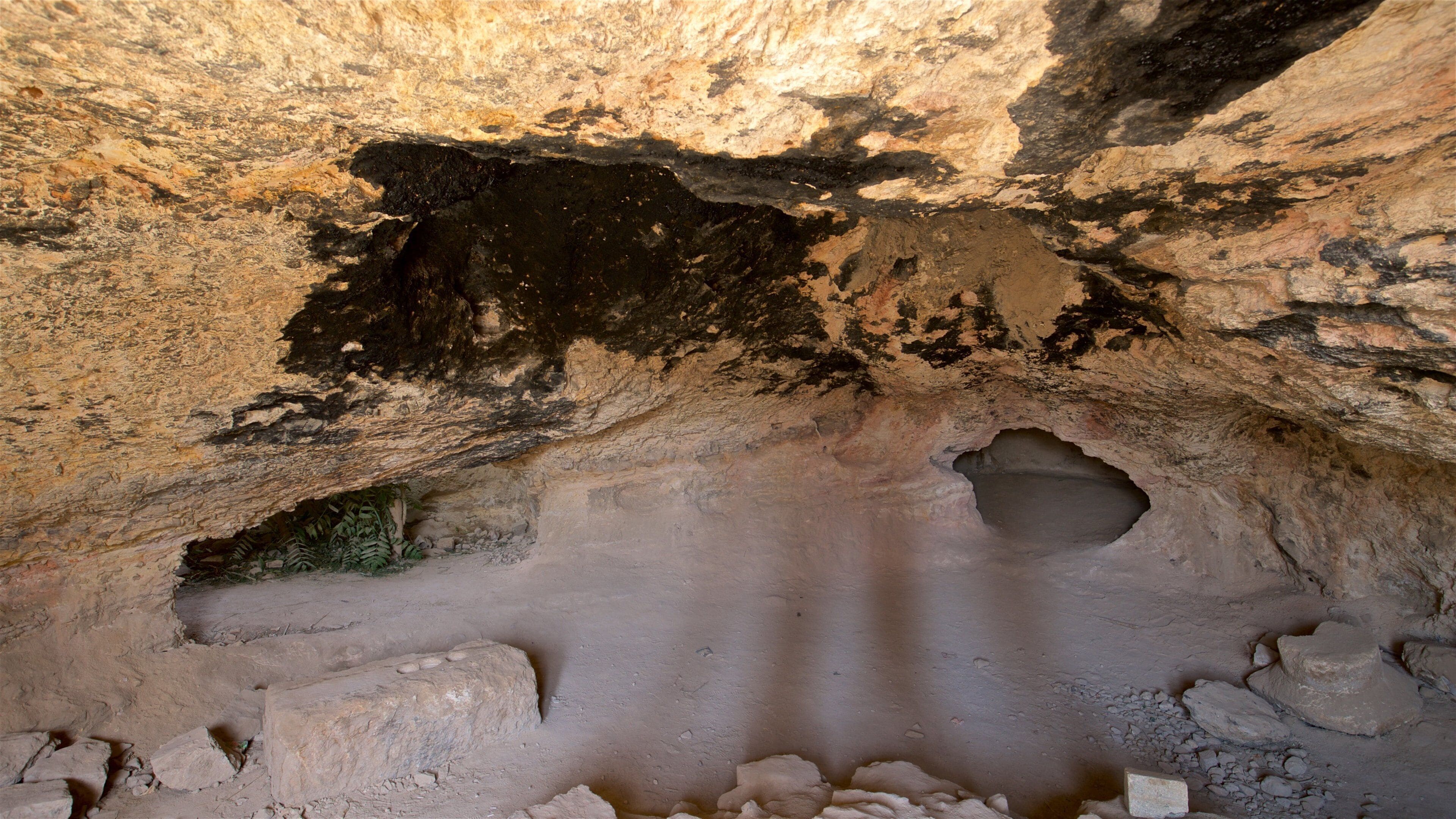 Interior de una cueva con formaciones rocosas y una gran abertura.