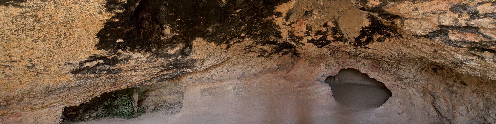 Interior de una cueva con formaciones rocosas y una gran abertura.