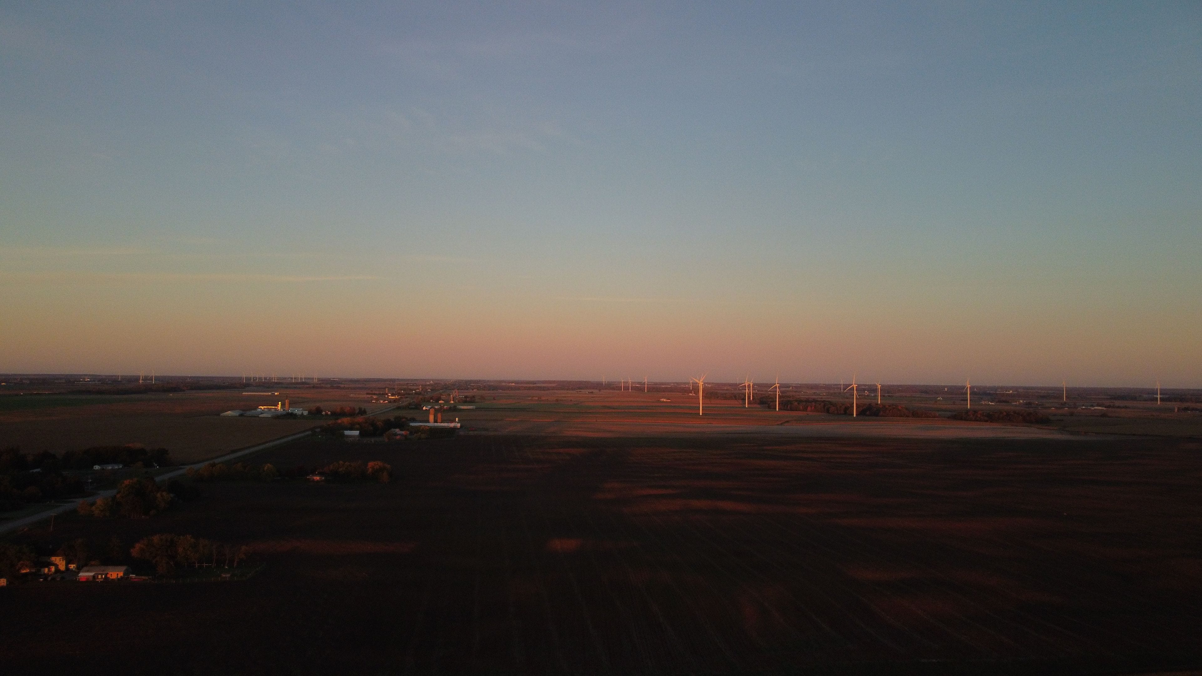 A rural landscape with wind turbines and fields.