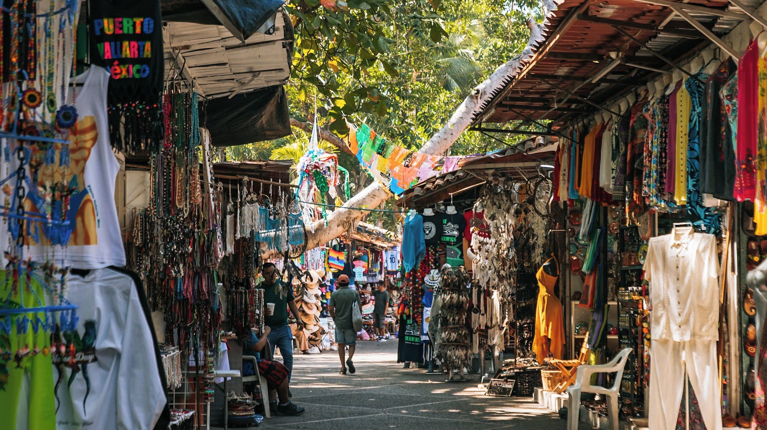 A bustling outdoor market with various stalls selling colorful textiles, jewelry, and clothing.