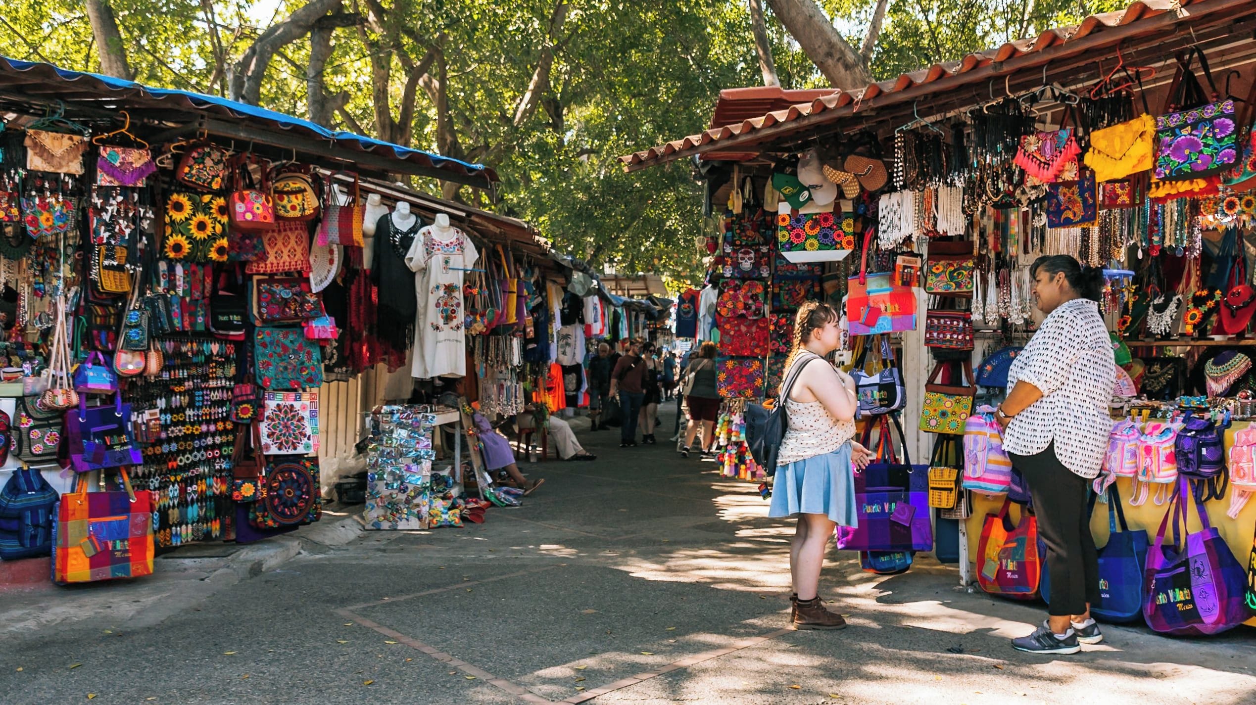 A bustling outdoor market with colorful bags and accessories.