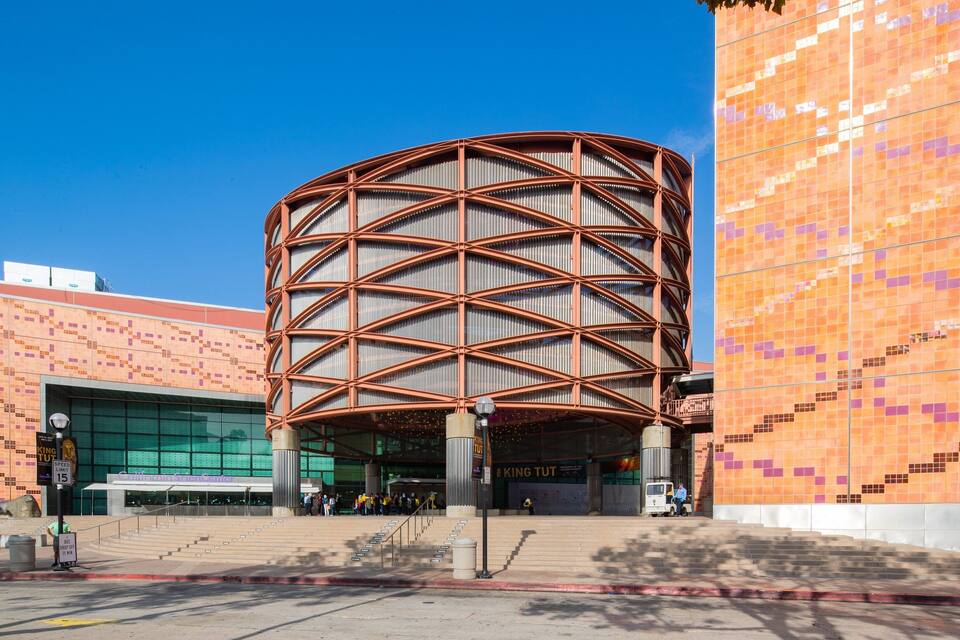 A modern building with a distinctive curved metal framework and a colorful mosaic wall.