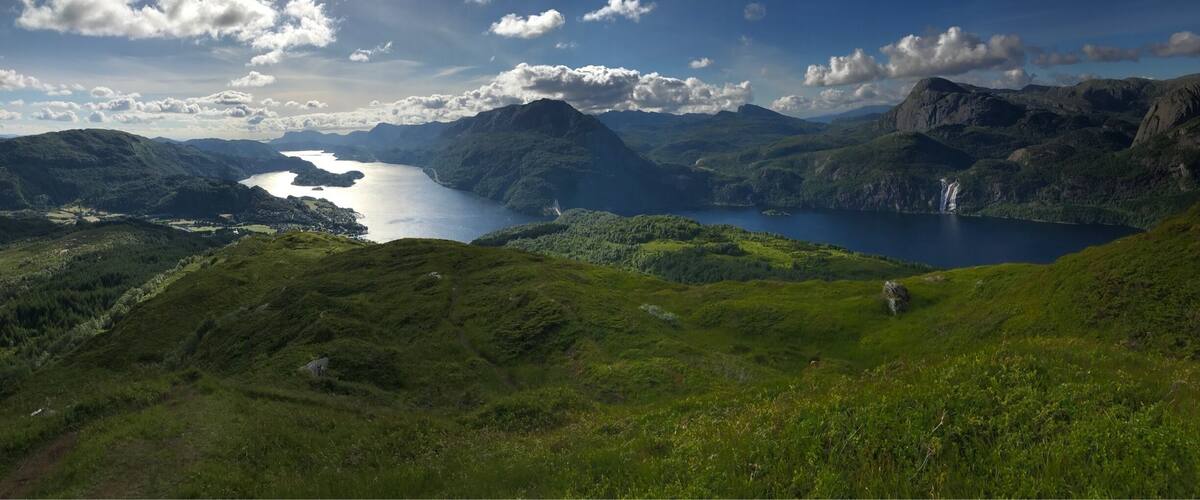 A mountainous landscape with a lake and a waterfall.