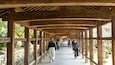 A wooden covered walkway with people walking.