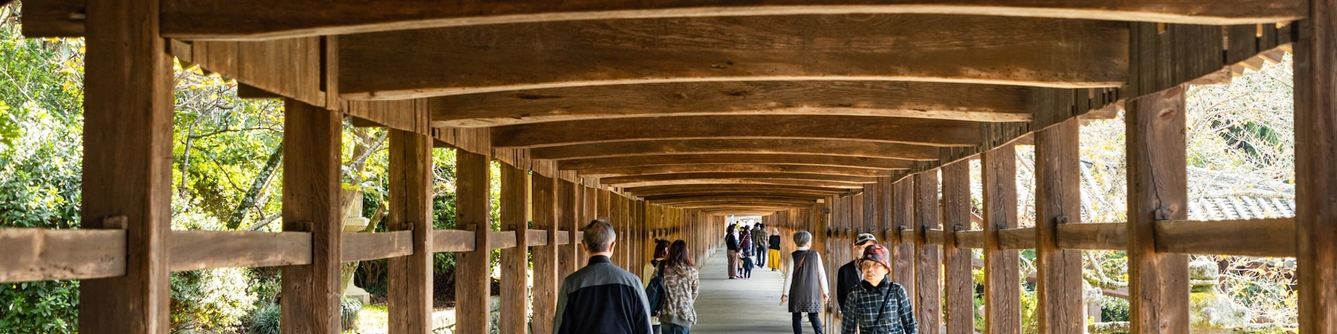 Uma passarela de madeira coberta com pessoas caminhando.