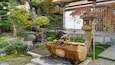 A traditional Japanese garden with a stone basin, bamboo, and various plants.