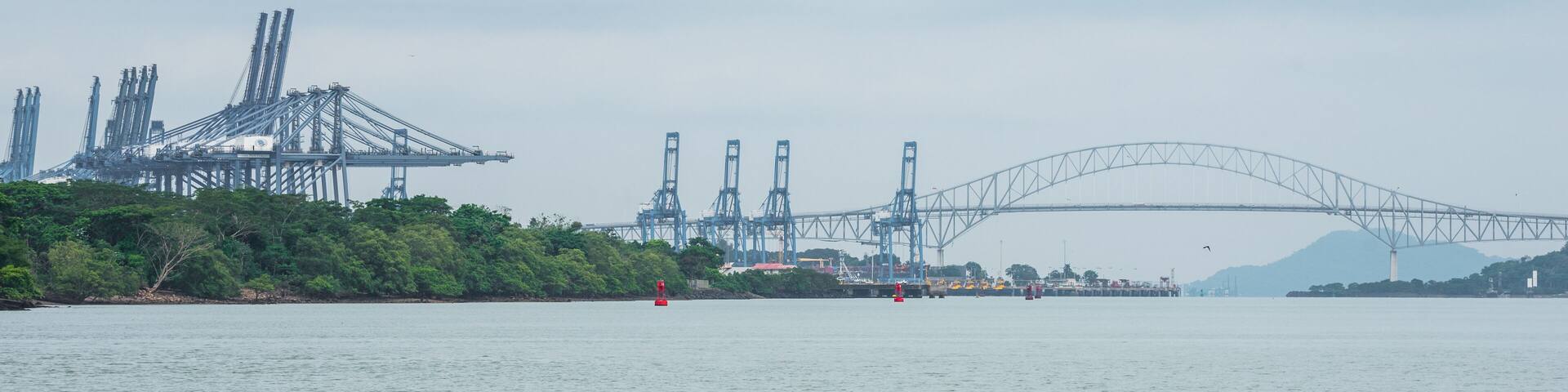 A large suspension bridge, industrial cranes, and a calm river.