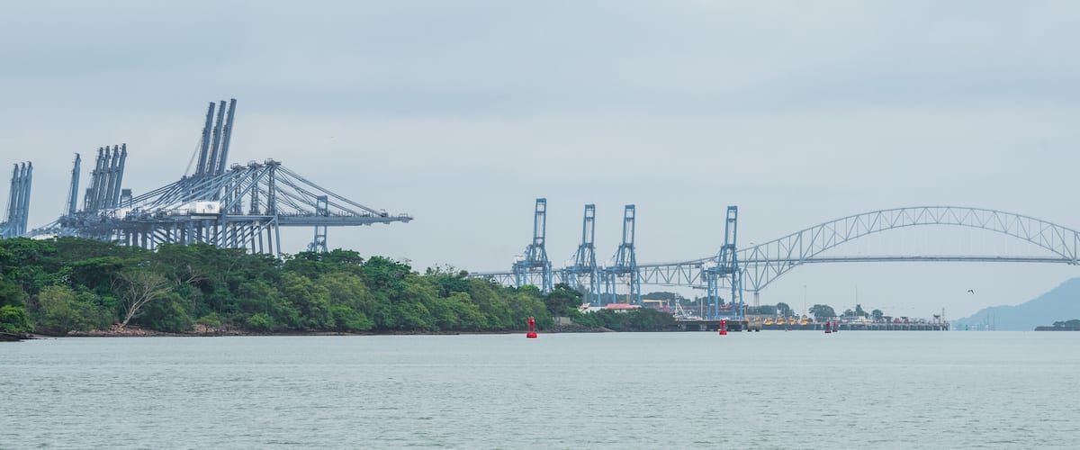 A large suspension bridge, industrial cranes, and a calm river.