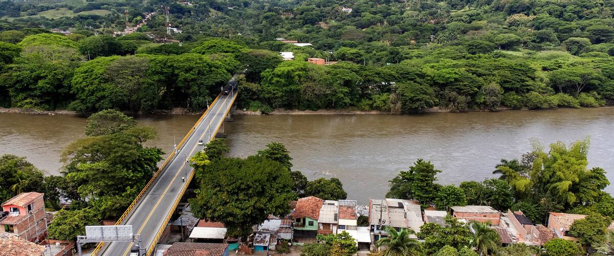 A river with a bridge, surrounded by lush greenery and small buildings.