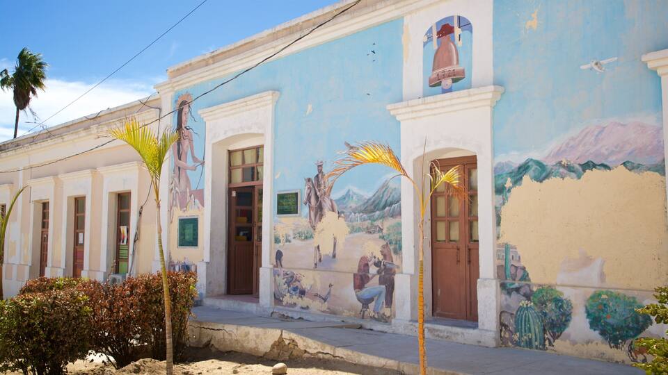 A building with a mural depicting a horse and rider, palm trees, and a bell.