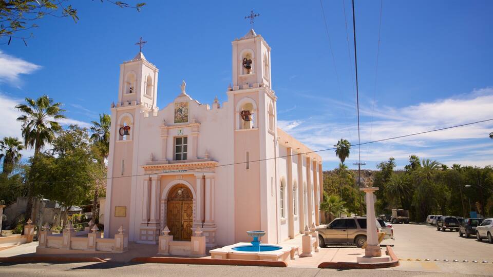 A pink church with two towers and a fountain in front.