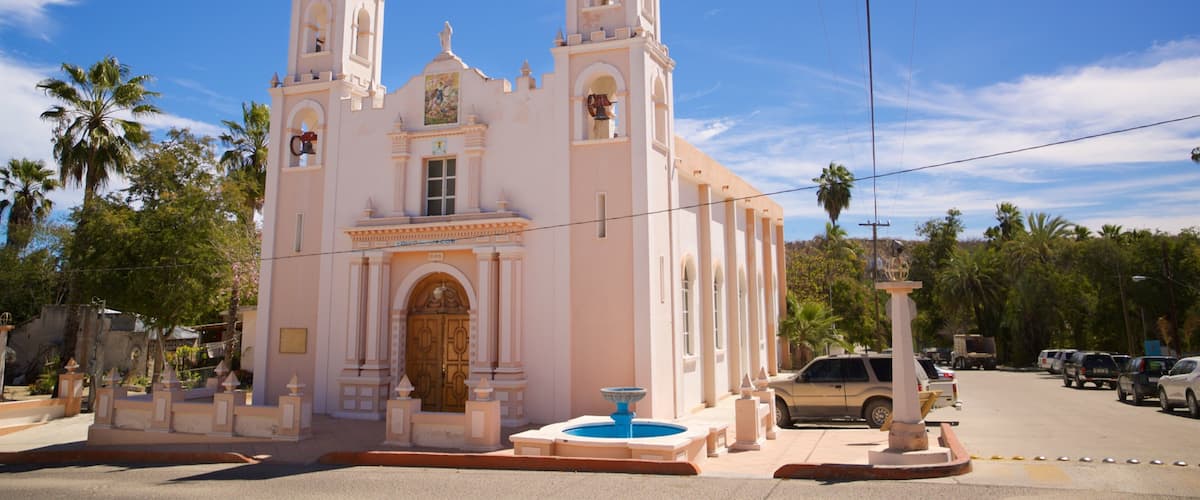 A pink church with two towers and a fountain in front.