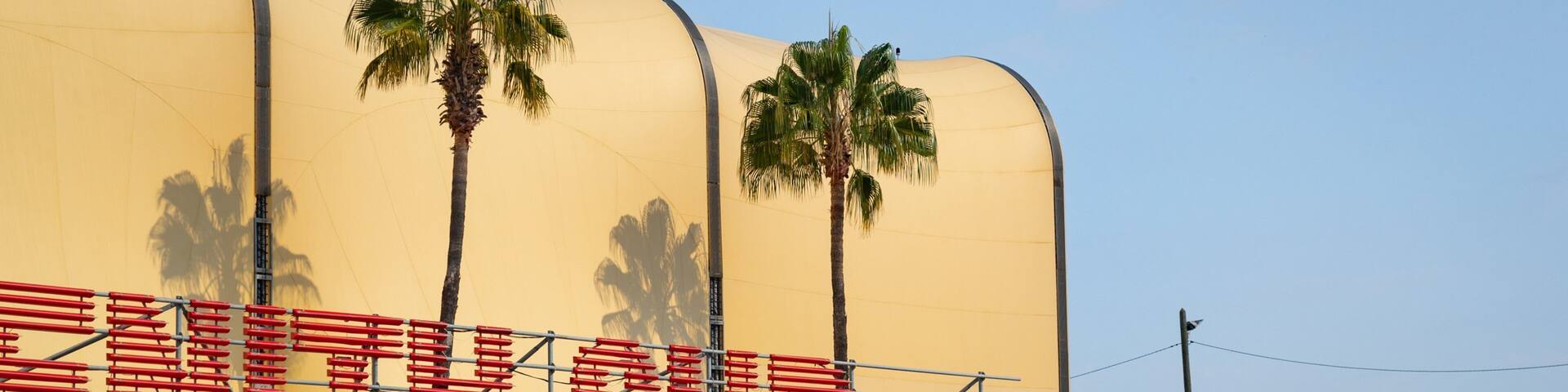 A large yellow tent with palm trees and a red structure with the text "LE ZENITH SUD" on it.