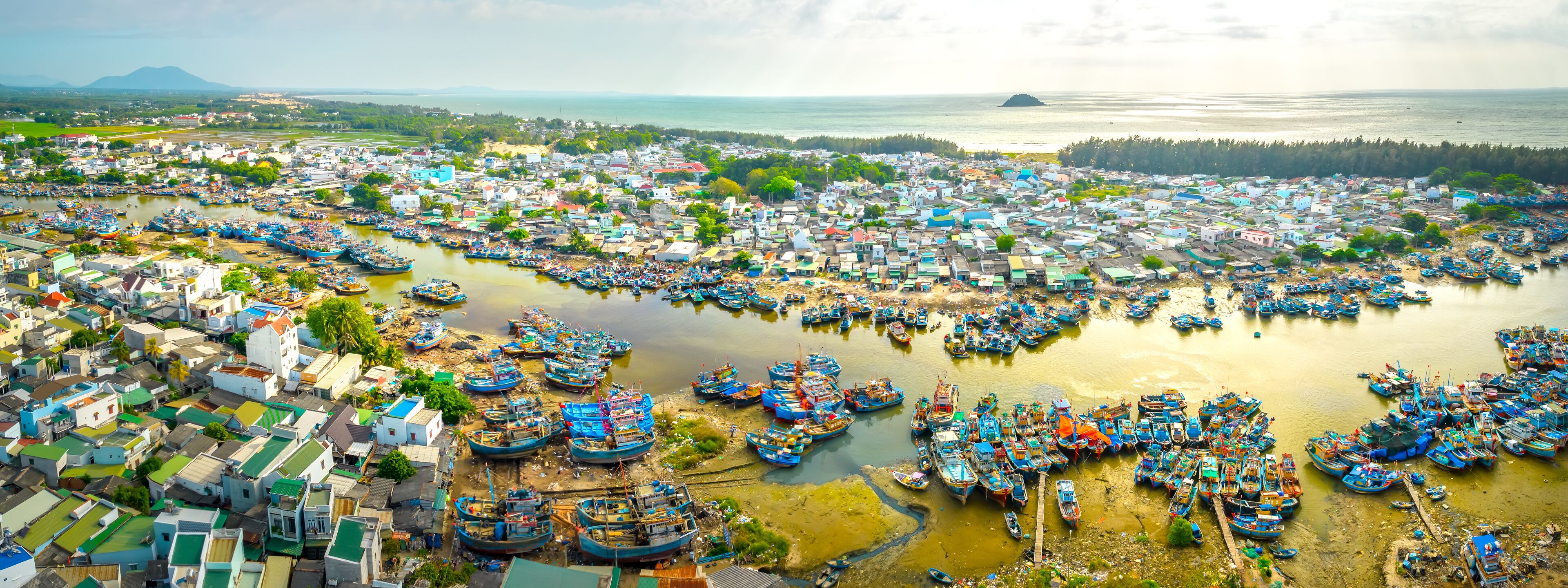 La Gi fishing village seen from above with hundreds of boats anchored along both sides of river to avoid storms near estuary, this is also a large fishing port providing seafood in central Vietnam